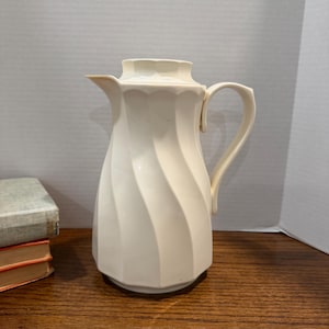 May include: A set of three ceramic mugs with a speckled, matte finish. The mugs are in shades of cream, light gray, and dark gray. Each mug has a simple, minimalist design and a rounded handle. The mugs are stacked on top of each other.