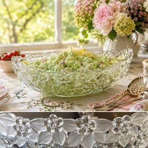 May include: A clear glass serving bowl featuring a decorative embossed floral pattern along the rim. The bowl has a scalloped edge with alternating frosted and polished glass flower petals. It is filled with a light green salad mixture.