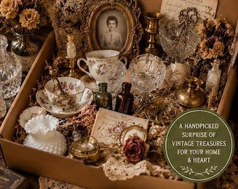 May include: A large cardboard box filled with vintage items including a gold-toned framed portrait, floral teacups, crystal glassware, small glass bottles, brass candlesticks, and dried flowers. Text reads: VINTAGE CURIOSITIES Mystery Box LARGE.