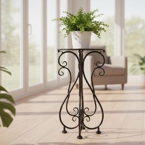 May include: A black wrought iron plant stand with a round top and decorative scrollwork. A white pot with a green plant sits on top. The stand is approximately 30 inches tall.