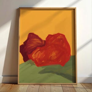 Puede incluir: Una impresión de arte mural rectangular enmarcada que presenta una pintura abstracta con un fondo amarillo vibrante, una gran forma roja texturizada en el centro y una base verde apagado. El marco es de madera clara. El texto Black Blot House es visible.