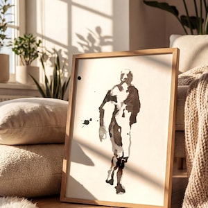 May include: A framed wall art piece featuring a minimalist black ink wash painting of a human figure in motion on a white background. The artwork is enclosed in a light-toned wooden frame, showcasing abstract brushstrokes and ink splatters.