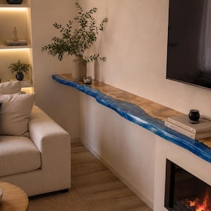 Peut inclure: Une longue étagère de cheminée horizontale composée d'une dalle de bois brut à bord naturel avec une incrustation de résine bleue vive traversant le centre, fixée au-dessus d'une cheminée et s'étendant le long du mur comme une corniche.