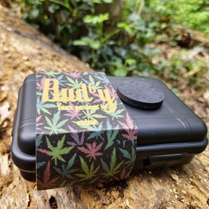 May include: White ceramic mug with a black handle, featuring the text "But First, Coffee" in black. The mug is displayed against a blurred backdrop, implying a comfortable environment.