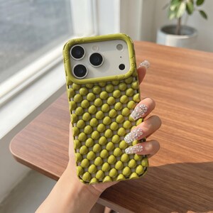 May include: A lime green smartphone case featuring a raised, bubble-like textured surface across the back. The camera module area is framed in a matching lime green border with the word YOKKE embossed along the top and side edges.