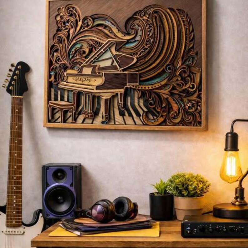 Pu&ograve; includere: Un'opera d'arte in legno incorniciata raffigura un pianoforte a coda con intricati dettagli a strati in tonalit&agrave; marroni e beige. L'opera d'arte &egrave; appesa sopra un tavolo di legno. Sono visibili anche una chitarra in bianco e nero, un altoparlante e delle cuffie.