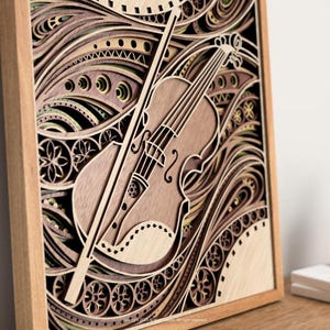 Puede incluir: Obra de arte de madera en capas que representa un violín y un arco. La obra está enmarcada en madera marrón claro y muestra intrincados diseños recortados en tonos de marrón, beige y verde. El violín es el punto focal, con cuerdas detalladas y un arco.