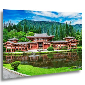 May include: A colourful image of a Japanese temple with red and brown architectural details, set against a backdrop of lush green trees and a mountain range. The temple is reflected in the calm water of a pond, under a blue sky.