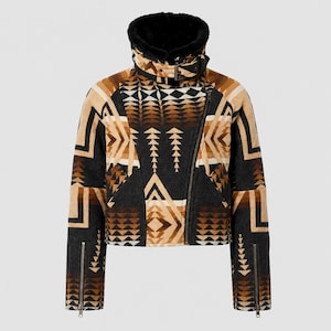 May include: A cropped jacket featuring a geometric pattern in shades of black, tan, and brown. The jacket has a high collar lined with black faux fur, an asymmetrical front zipper closure, a buckled neck strap, and zippered cuffs on long sleeves.