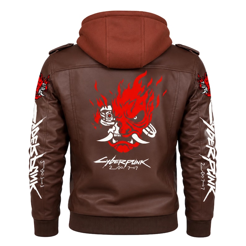 May include: A brown hooded jacket featuring a red and white graphic of a stylized oni mask on the back, with the text Cyberpunk 2077 printed below. The sleeves display white text and small red mask graphics, with shoulder epaulets and ribbed cuffs.