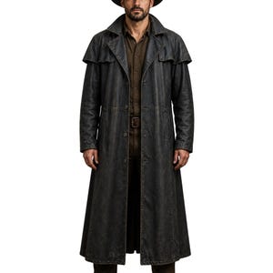 May include: A long, dark grey duster coat with a distressed finish. The coat features a wide collar, shoulder cape, and a button-down front. The coat is worn with a brown shirt and belt, and a dark hat.