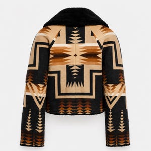 May include: A cropped jacket featuring a black faux fur collar and a geometric pattern in shades of tan, brown, and black. The design includes repeating triangular and chevron motifs across the back and sleeves, with a black hem and cuffs.