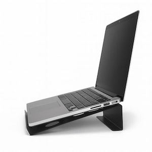 Peut inclure: Un ordinateur portable argenté est posé sur un support noir. L'écran de l'ordinateur portable est ouvert et incliné vers le haut. Le support est fait d'un matériau solide et a un design minimaliste, élevant l'ordinateur portable pour une meilleure ergonomie. Le support mesure environ 25 cm.