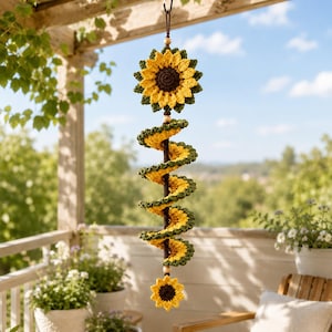 May include: A hanging crochet spiral decoration featuring a large sunflower at the top and a smaller sunflower at the bottom. The spiral is crafted with yellow and green yarn, connected by a central brown cord with wooden beads for spacing.