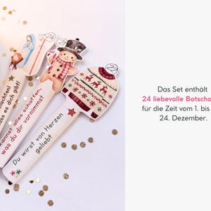 May include: Three die-cut paper strips featuring Christmas illustrations of a nativity scene, a gingerbread person, and a patterned sweater, each labeled with numbers 24, 21, and 22, and printed with German text messages for the holiday season.