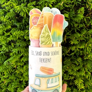 May include: A cylindrical container featuring a graphic of an ice cream truck and the German text Eis, Spa&szlig; und Sch&ouml;ne Ferien. The top is decorated with various die-cut paper illustrations of colorful ice cream cones, popsicles, and sorbet.