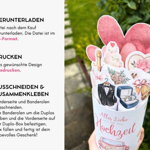 May include: A DIY wedding gift box project featuring a white cylindrical container with the text Alles Liebe Hochzeit, decorated with paper cutouts of a tuxedo, wedding rings, champagne, flowers, bells, and pink hearts on a white background.