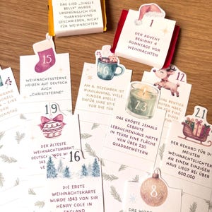 May include: A collection of rectangular advent calendar cards featuring numbered tabs from 1 to 23, each decorated with festive illustrations like a star, Santa hat, stocking, mug, reindeer, candle, ornament, and sleigh, containing German text.