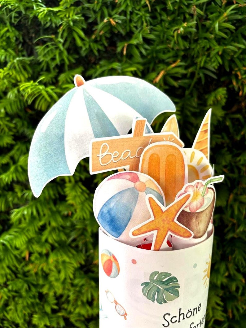 May include: A cylindrical container decorated with beach-themed icons including a beach ball, a monstera leaf, and sunglasses. The top features cutouts of a blue and white umbrella, a wooden beach sign, an orange popsicle, and a coconut drink.