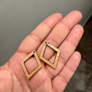 May include: Two unfinished wooden diamond-shaped earrings with a hole at the top for hanging.