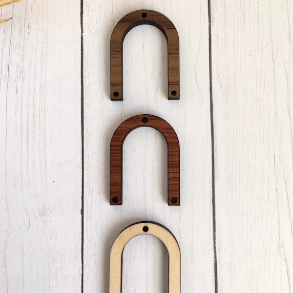 Op de afbeelding: Drie houten bogen in verschillende bruintinten. De bogen zijn allemaal even groot en even gevormd en hebben twee gaten aan de onderkant.