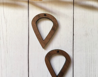 May include: Two wooden teardrop-shaped earring blanks with a hole at the top. The blanks are a light brown color and have a smooth finish.