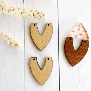 May include: Three unfinished wooden heart shapes with holes at the top. Two are natural wood and one is stained a dark brown.