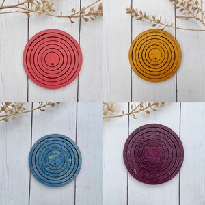 May include: Four wooden circles with concentric rings in different colors: red, yellow, blue, and purple. Each circle has a small hole in the center.