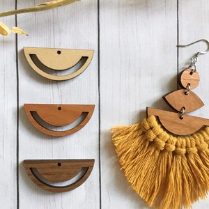 May include: Three unfinished wooden half-circle shapes with holes for hanging. The shapes are in natural wood, reddish brown wood, and dark brown wood. A pair of earrings with a yellow tassel and wooden shapes are shown on the right.