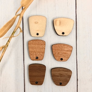 May include: Six wooden tags in three different wood tones: light, medium, and dark. Each tag has a rounded top and a hole at the bottom for hanging.