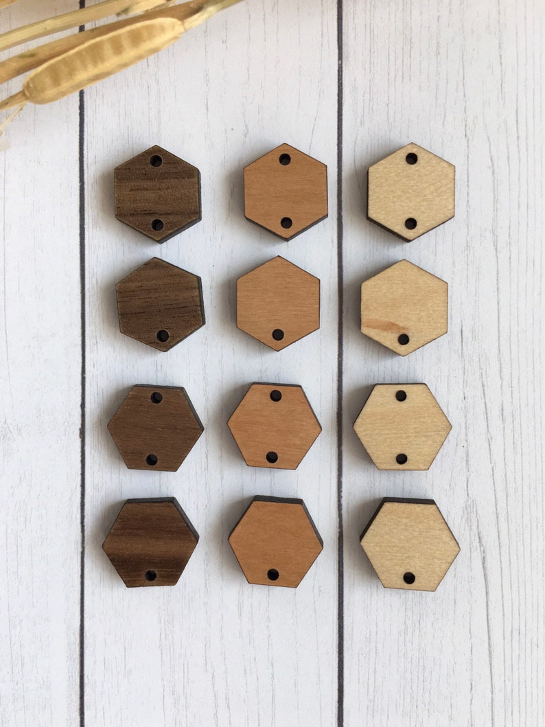 May include: Twelve wooden hexagon shapes, three rows of four. The top row is dark brown, the middle row is light brown, and the bottom row is a medium brown. Each hexagon has two holes.