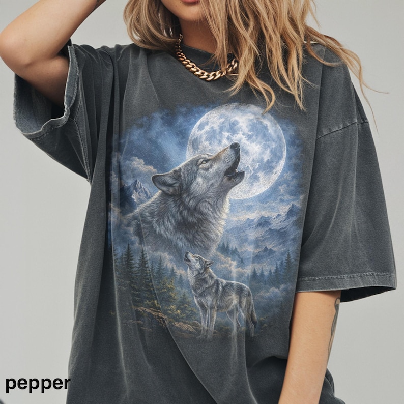 May include: Dark gray oversized t-shirt featuring a wolf howling at a full moon. The graphic includes a second wolf and a mountain landscape with a blue and white sky. The word "pepper" is printed at the bottom left.