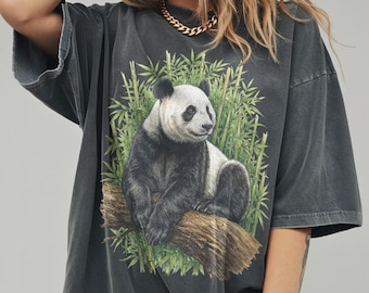 May include: Dark grey oversized t-shirt with a panda bear illustration. The panda is depicted sitting on a log with bamboo behind it. The shirt has a faded appearance. The panda is black and white, and the bamboo is green.