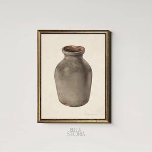 May include: A framed print featuring a vintage stoneware jug. The jug is a muted gray color with a slightly textured surface and a dark brown interior. The print is set against a cream-colored background and framed in gold.