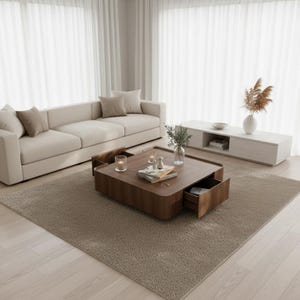 May include: A contemporary living room featuring a beige sofa, a wooden coffee table with an open drawer, and a white entertainment unit. The room has a neutral colour palette with a beige rug and white curtains.