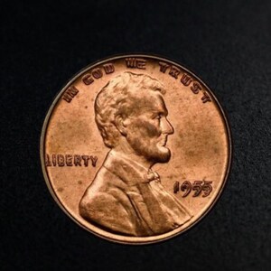 Puede incluir: Una moneda estadounidense de 1955 de color cobre. La moneda presenta el perfil de un hombre, las palabras "IN GOD WE TRUST" y "LIBERTY", y el año "1955". La moneda es redonda y tiene un aspecto ligeramente desgastado.