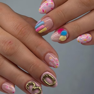 May include: Oval-shaped nails with a pale pink base, adorned with colourful sprinkles, 3D candles, and balloons. One nail features a gold '30' design. The nails have a glossy finish.