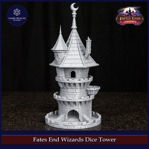 May include: A gray stone wizard's tower dice tower with a crescent moon on top. The tower has three levels with openings for dice to roll out. The tower is made of a 3D printed material and has a stone texture. The tower is labeled "Fates End Wizards Dice Tower".