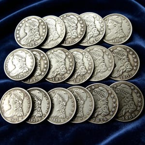 May include: A collection of silver-toned coins featuring the profile of a figure wearing a cap inscribed with the word LIBERTY, surrounded by stars. Each coin is marked with a specific year, including 1807, 1808, 1809, 1810, 1811, 1812, 1813, 1814, 1815, 1817, 1824, 1837, 1838, and 1839.