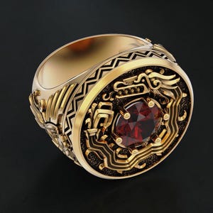 Könnte beinhalten: Ein goldfarbener Ring mit aufwendigen Details und einem großen, ovalen, roten Edelstein in der Mitte. Der Ring weist verzierte Muster und Designs um den Edelstein und auf dem Band auf, vor dunklem Hintergrund.