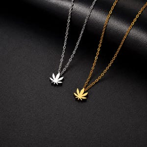 Puede incluir: Dos collares con cadenas de eslabones finos, uno en tono plateado y otro en tono dorado. Cada collar presenta un pequeño colgante plano con forma de hoja de cannabis de siete puntas. Los colgantes son sólidos y del mismo color.