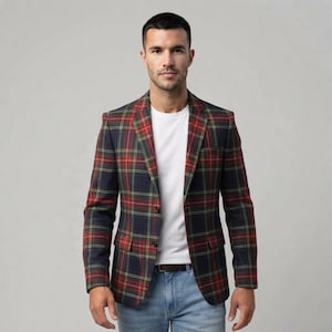 May include: A navy blue blazer featuring a red, green, and yellow plaid pattern, worn over a plain white crew neck t-shirt and light blue denim jeans with a brown leather belt. The blazer has notched lapels and two front buttons.