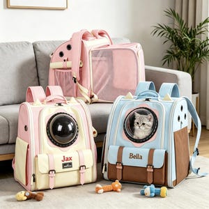 May include: Three pet carrier backpacks in pink, cream, and light blue. Each features a circular bubble window, adjustable shoulder straps, and a front pocket. One blue backpack displays the name Bella, while the cream one displays the name Jax.