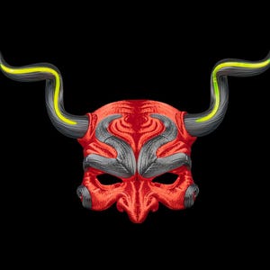 May include: A red mask featuring a textured surface with dark gray accents around the eyes and forehead. The mask includes two large, curved horns extending outward, each detailed with a bright yellow stripe running along the top edge.