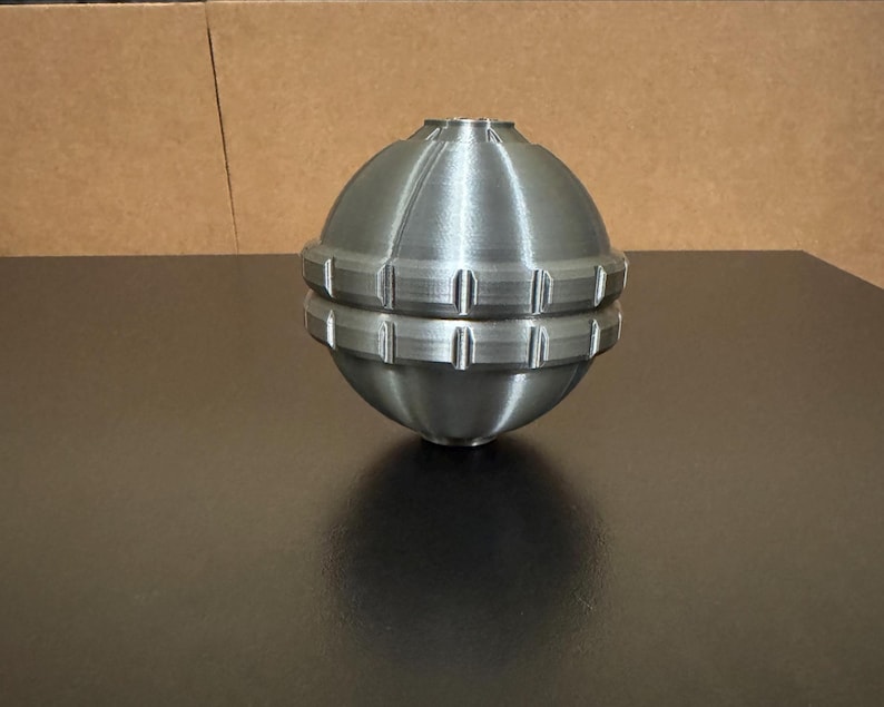 May include: A white ceramic mug with a black handle and the text "But First, Coffee" in a bold, black font. The mug is set against a blurred background, highlighting its simple design.