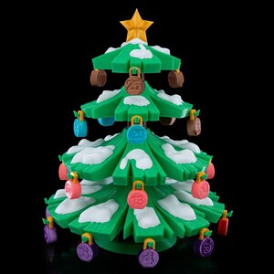 Pode incluir: Uma árvore de Natal impressa em 3D verde com detalhes de neve branca nos ramos e uma estrela amarela no topo. A árvore apresenta pequenas etiquetas circulares coloridas penduradas, cada uma com um número gravado, incluindo 5, 13, 20 e 25.