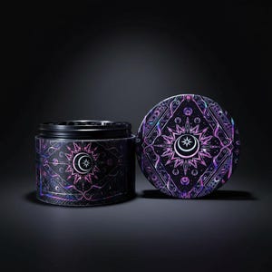 Pode incluir: Um frasco preto com uma tampa a condizer, ambos adornados com um design celestial. O design apresenta um sol, uma lua crescente e uma estrela em tons de roxo, rosa e iridescentes. O frasco está aberto, revelando o seu conteúdo.