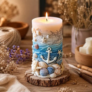 Peut inclure: Une bougie cylindrique allumée sur le thème nautique. La bougie présente un motif de carte, des vagues océaniques, une ancre, des coquillages et des étoiles de mer. Elle repose sur une base en bois, créant une esthétique côtière.