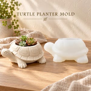 May include: A turtle planter mold and a finished off-white turtle-shaped planter containing small green succulents. The text TURTLE PLANTER MOLD is visible at the top. The mold is translucent white, while the finished planter has a matte texture.