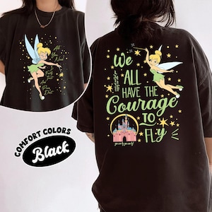 May include: A black t-shirt featuring Tinker Bell graphics. The front shows Tinker Bell with the text All You Need Is Faith Trust And Pixie Dust. The back displays Tinker Bell, a castle, stars, and the text We All Have The Courage To Fly.
